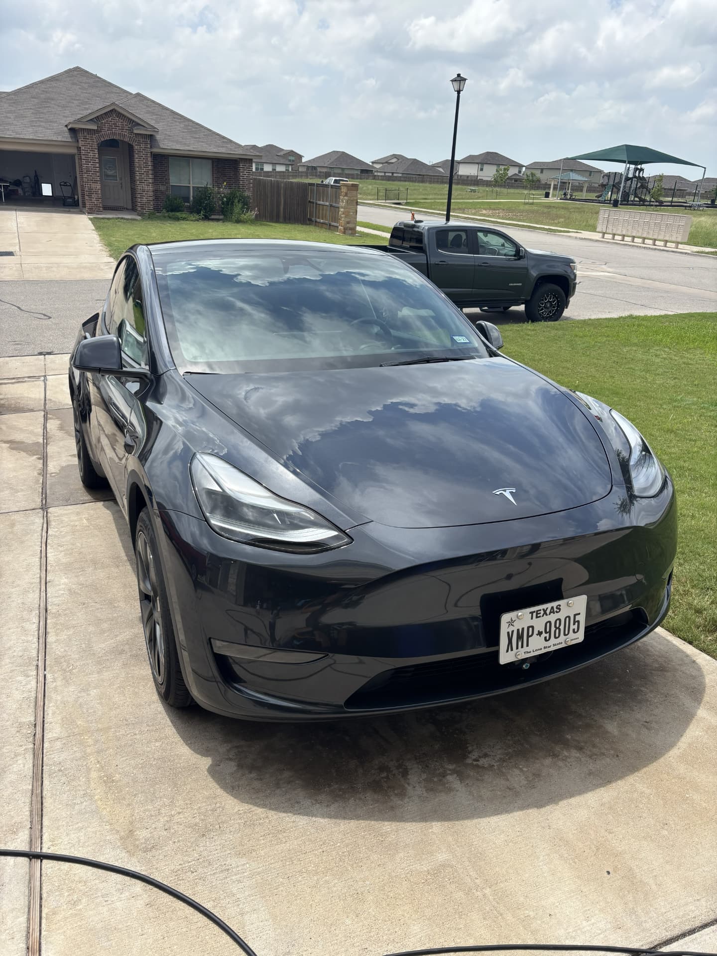 Black Tesla Model Y with a mirror shine in a driveway